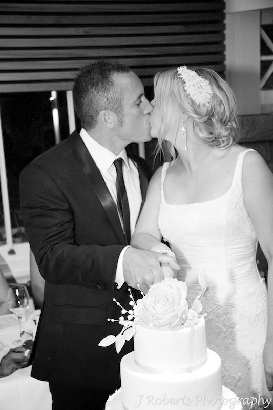 Bride and groom kissing after cutting the wedding cake - wedding photography sydney